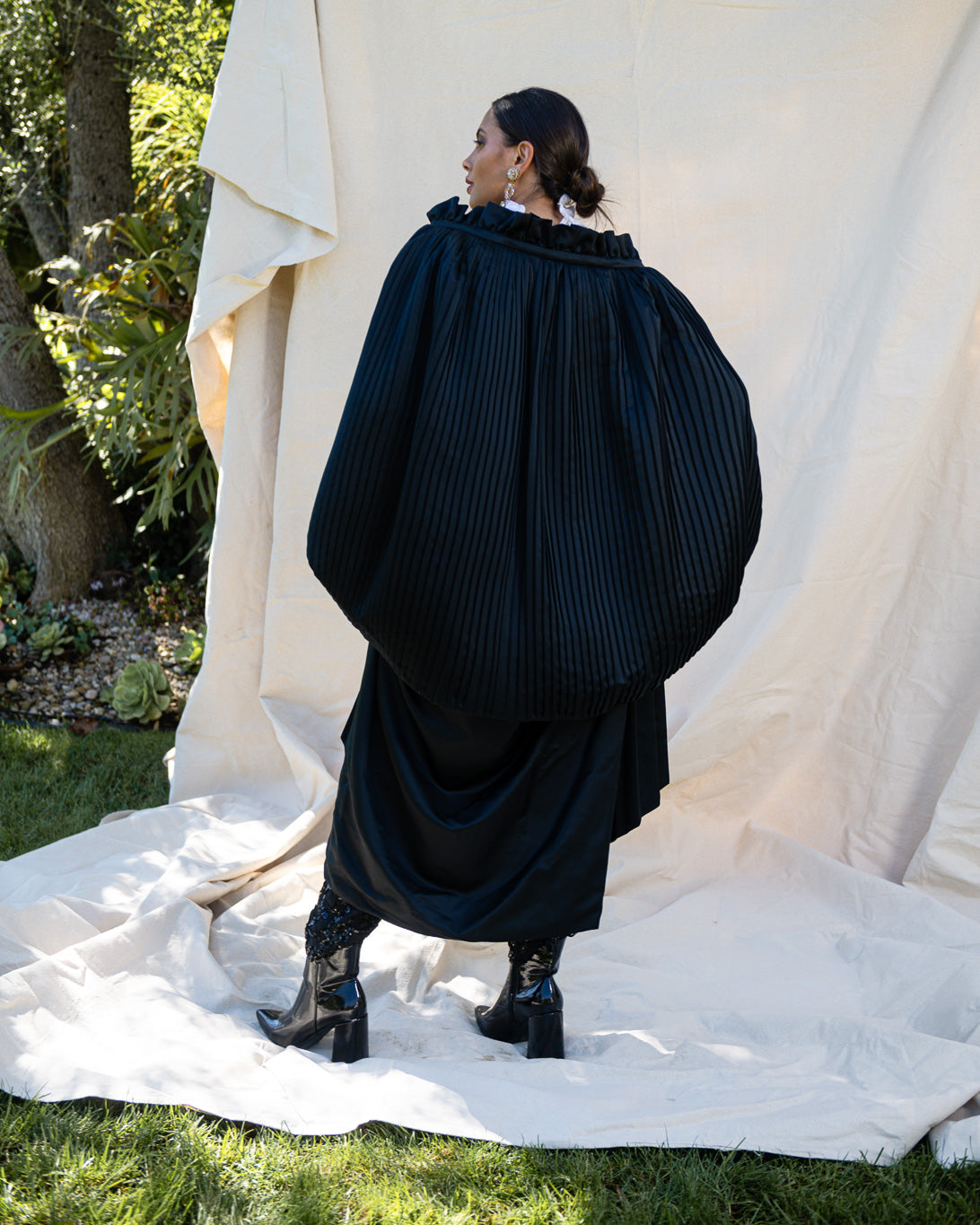 Pleated Cocoon Coat by Calderon on model in front of canvas showing back