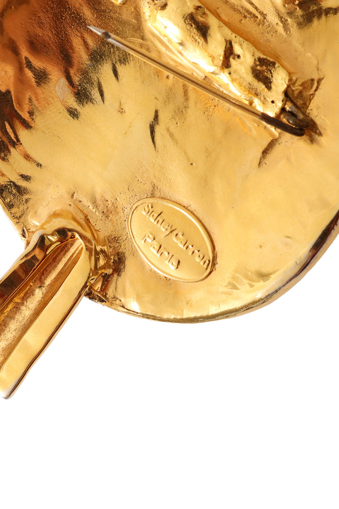 Golden abstract dagger plate pin by Sidney Cannon backside signature up close @ Recess LA 