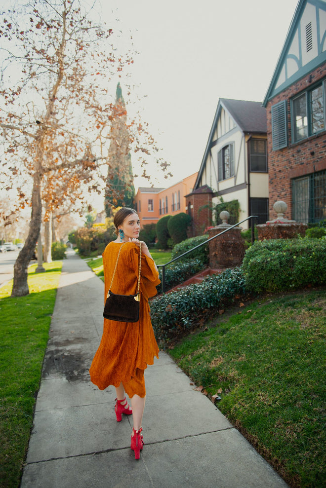 Girl in orange outfit with Gucci Monogram Chenille Bag from Recess on sidewalk