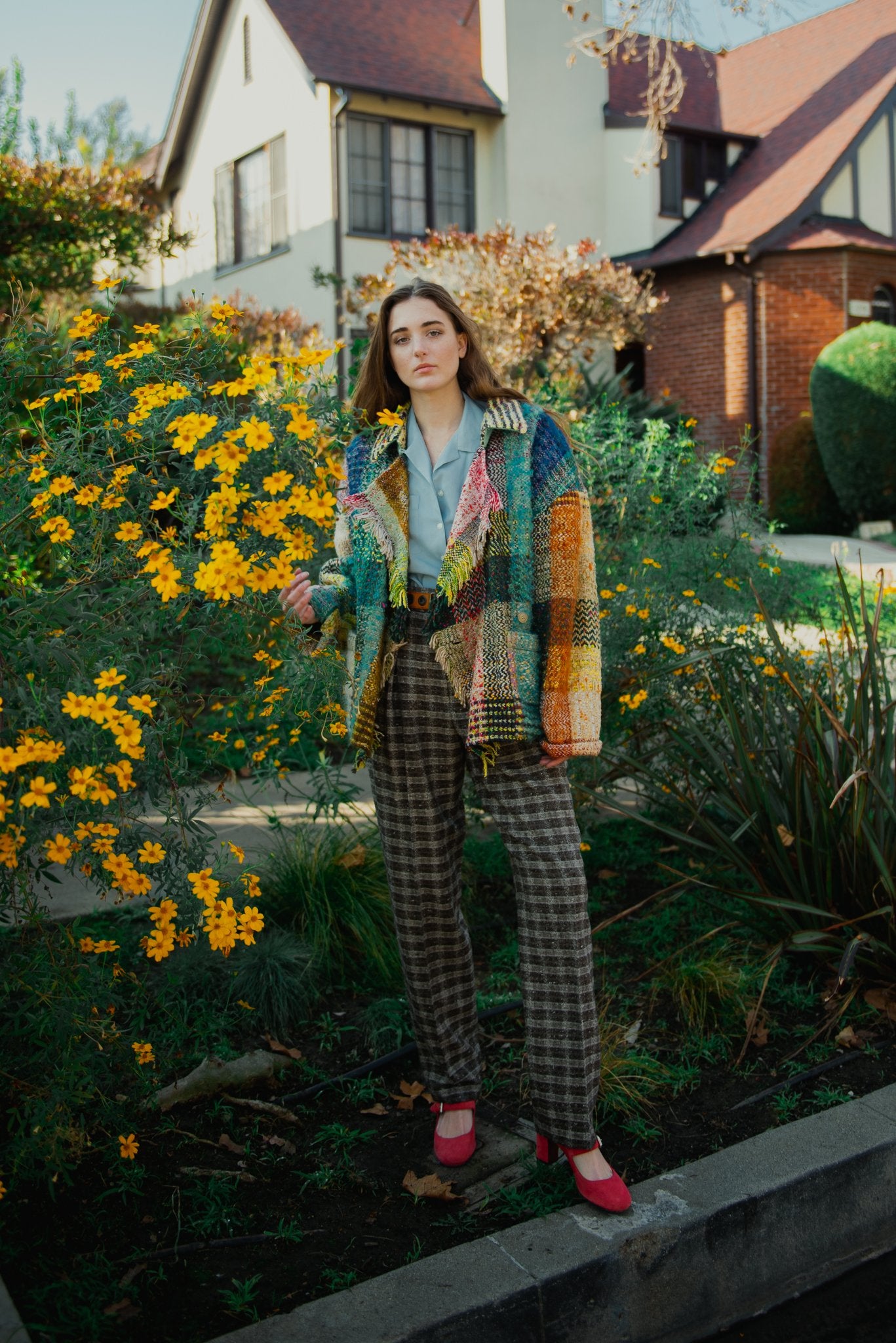 Girl in vintage Jean Charles de Castelbajac rainbow blanket coat from Recess by yellow flowers